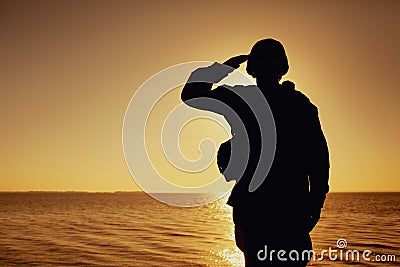 Silhouette of soldier salutes on sunset background Stock Photo