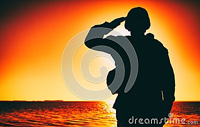 Silhouette of soldier salutes on sunset background Stock Photo