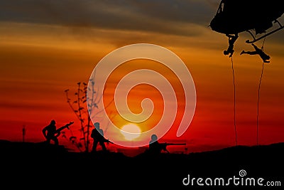 Silhouette Soldiers rappel down to attack from helicopter with sunset and copy space add text Concept stop hostilities To peace Stock Photo