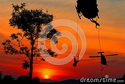 Silhouette Soldiers rappel down to attack from helicopter with sunset and copy space add text Concept stop hostilities To peace Stock Photo