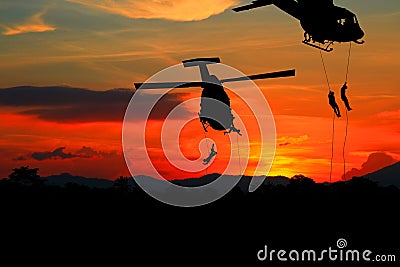 Silhouette Soldiers rappel down to attack from helicopter with sunset Stock Photo