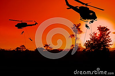 Silhouette Soldiers rappel down to attack from helicopter with sunset Stock Photo