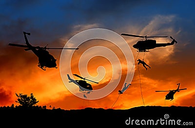 Silhouette Soldiers rappel down to attack from helicopter with sunset Stock Photo