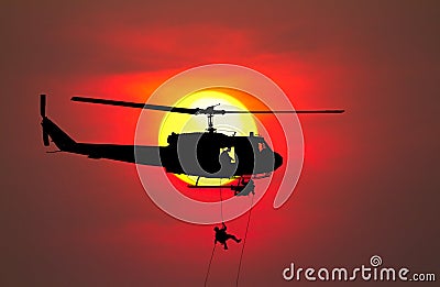 Silhouette Soldiers rappel down to attack from helicopter with warrior beware danger On the ground sunset Background blur Stock Photo