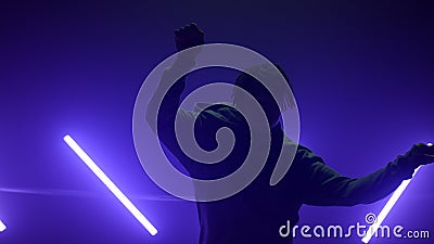 Silhouette b-boy making hands movements breakdance in club. Guy dancing hiphop Stock Photo