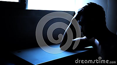 Silhouette of a depressed man in a dark room. Mental health, depression and feeling blue concept Stock Photo