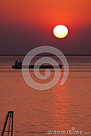 Silhouette of tank ship moored at anchor against red sunset sky Stock Photo