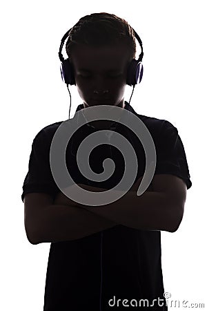 Silhouette of teenager listening to music in headphones, guy folded his arms on the chest on white isolated background, concept Stock Photo