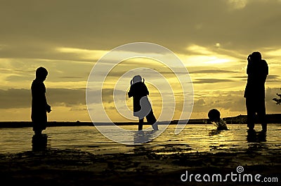 Silhouette three boys plays beach ball and moment the ball falling during sunset sunrise Stock Photo