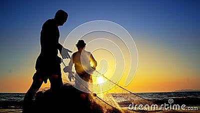 Silhouette of traditional fishermens pulling net fishing at ocean coast at sunset Editorial Stock Photo