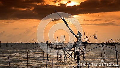 Silhouette of traditional fishing method using a bamboo square dip net with sunrise sky background Stock Photo