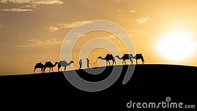 Silhouette of two Berber men leading camel caravans Stock Photo