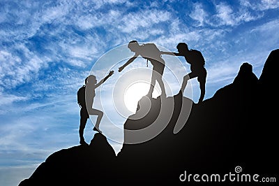 Silhouette of two female mountaineers helping another female mountaineer to overcome the obstacle in the mountains Stock Photo