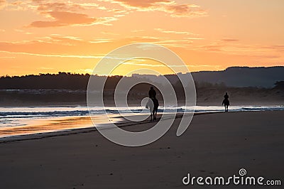 Silhouette of two horse riders on a beach at sunrise. Somo, Spain Stock Photo