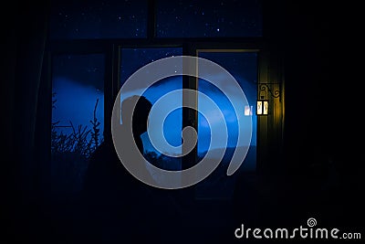 Silhouette of an unknown shadow figure on a door through a closed glass door. The silhouette of a human in front of a window at Stock Photo