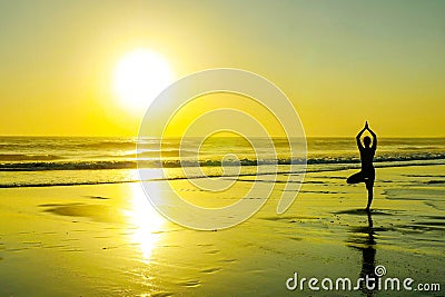 Silhouette of unknown unrecognizable woman standing on beach sea water practicing yoga and meditation looking to the sun on the ho Stock Photo