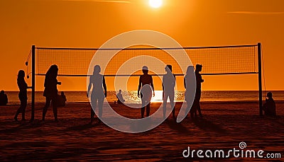 Silhouette volleyball game at sunset on beach generated by AI Stock Photo