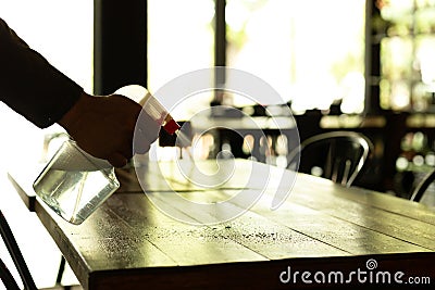 Silhouette waiter cleaning the table with disinfectant spray in a restaurant. Stock Photo