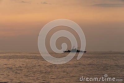 Silhouette of a warship sails along the trade route to protect national resources from illegal activities at sea Stock Photo