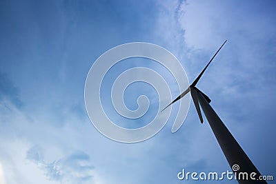 The silhouette of wind turbine on look up view on blue sky background. Stock Photo