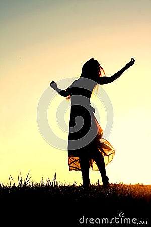 Silhouette of Woman Dancing and Praising God at Sunset Stock Photo