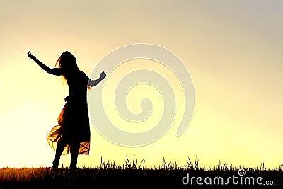 Silhouette of Woman Dancing and Praising God at Sunset Stock Photo