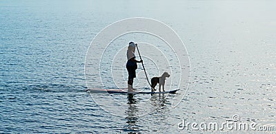 Silhouette woman and dog on standup paddleboard. Editorial Stock Photo