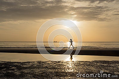 Silhouette of woman doing a brisk walking on the beach at sunset Stock Photo