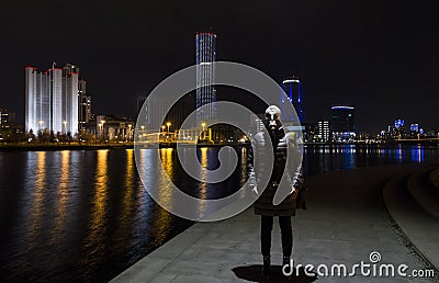 Silhouette of a woman in a gas mask against the background of a night city and a pond, the concept of the Apocalypse of the Stock Photo