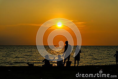 silhouette woman give food to family on beach sunset Editorial Stock Photo