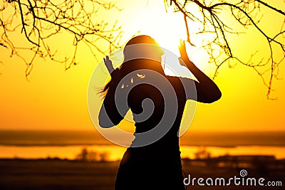 Silhouette of a woman in headphones, the girl enjoying music on the sunset Stock Photo