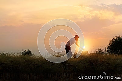 Silhouette of woman reaching hand to the sun beautiful field Stock Photo