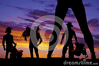 Silhouette of woman's legs and three cowboys in the sunset Stock Photo