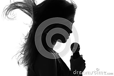 Silhouette of a woman singing with a microphone in hands Stock Photo