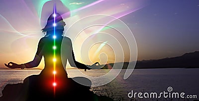 Silhouette of woman sits in a otus pose on beach sunset view, glowing seven all chakra. Kundalini energy. girl practicing yoga Stock Photo