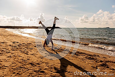 Silhouette woman somersault and exercise on the beach sunset. Stock Photo