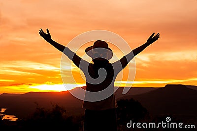Silhouette woman stands on mountain top at sunset time Stock Photo