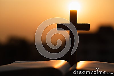 Silhouette of the wooden cross over opened bible with a bright sunrise as background , Christian, god Stock Photo