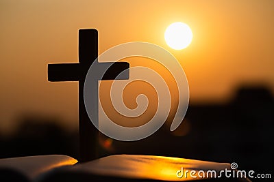 Silhouette of the wooden cross over opened bible with a bright sunrise as background , Christian, god Stock Photo