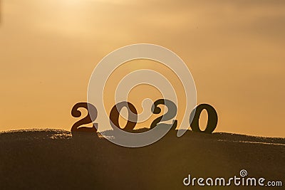 Silhouette of 2020 wooden numbers on the sand on the beach at sunset. Setting sun. The symbol of the outgoing year. 2021. Stock Photo