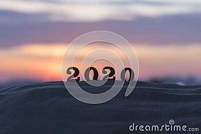 Silhouette of 2020 wooden numbers on the sand on the beach at sunset. Setting sun. The symbol of the outgoing year. Stock Photo