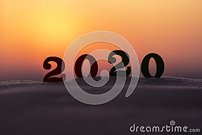 Silhouette of 2020 wooden numbers on the sand on the beach at sunset. Setting sun. The symbol of the outgoing year. Stock Photo