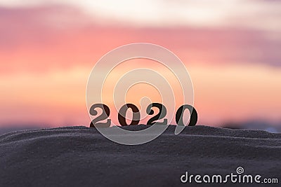 Silhouette of 2020 wooden numbers on the sand on the beach at sunset. Setting sun. The symbol of the outgoing year. Stock Photo