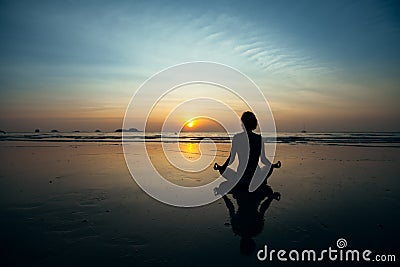 Silhouette yoga woman on the ocean beach at amazing sunset. Stock Photo