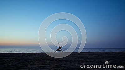 Silhouette yoga woman training warrior asana in front beautiful sunset sky. Stock Photo