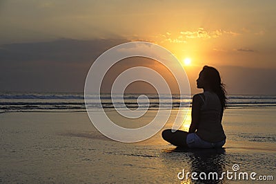 Silhouette of young beautiful asian woman sitting on sand water free and relaxed looking at the sun on sunset beach Stock Photo