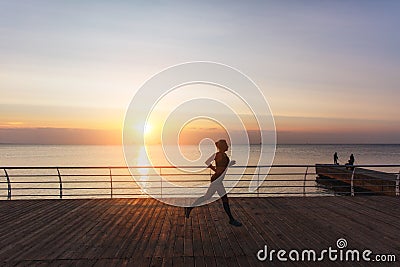 Silhouette of a young beautiful athletic girl with long blond hair in headphones, who listens to music and runs at dawn over the s Stock Photo