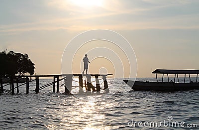 Silhouette of young boy on wooden walkway to the Bajau Village Stock Photo