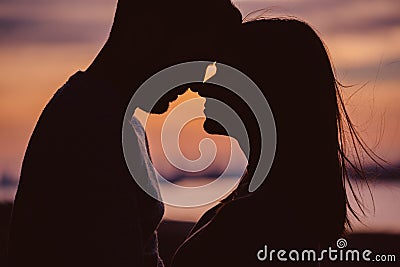 Silhouette of young couple having romantic moments against the sunset background Stock Photo