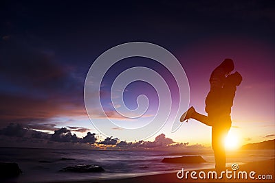 silhouette of young couple in love hugging on beach Stock Photo